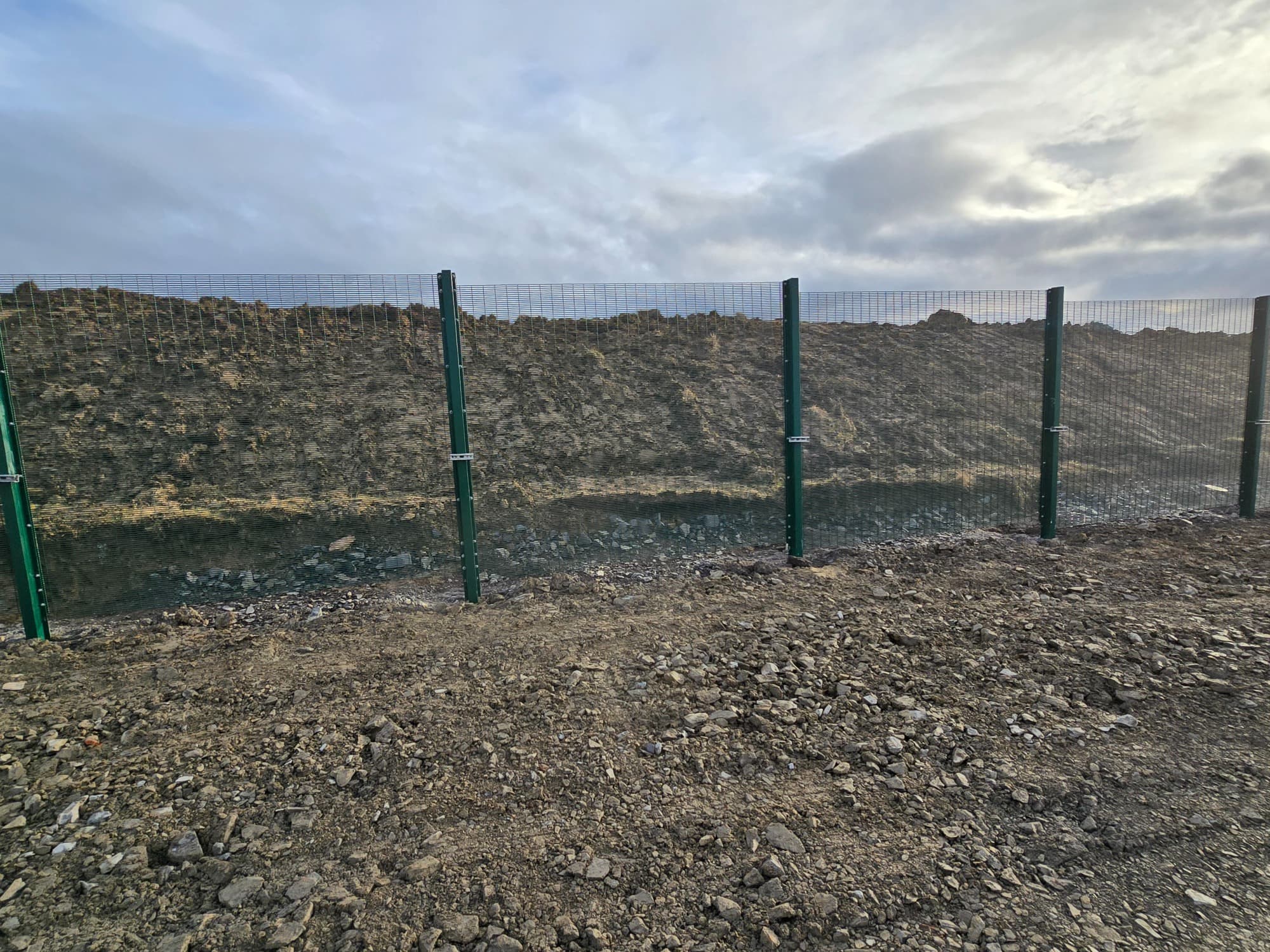 Dark green anti-climb mesh on square posts — typical commercial and site perimeter work.