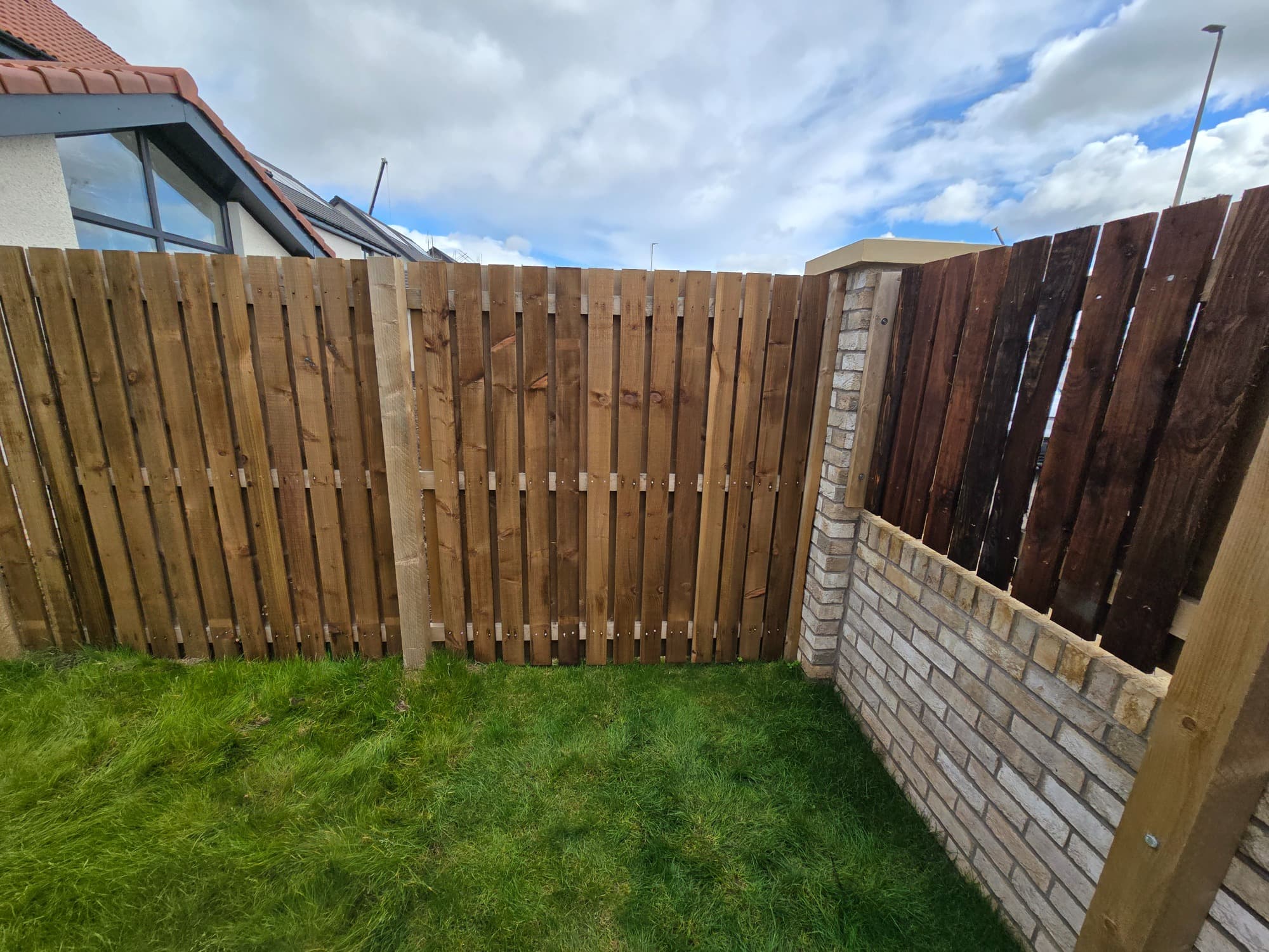Vertical timber on a brick plinth, giving a clean line between neighbouring gardens.