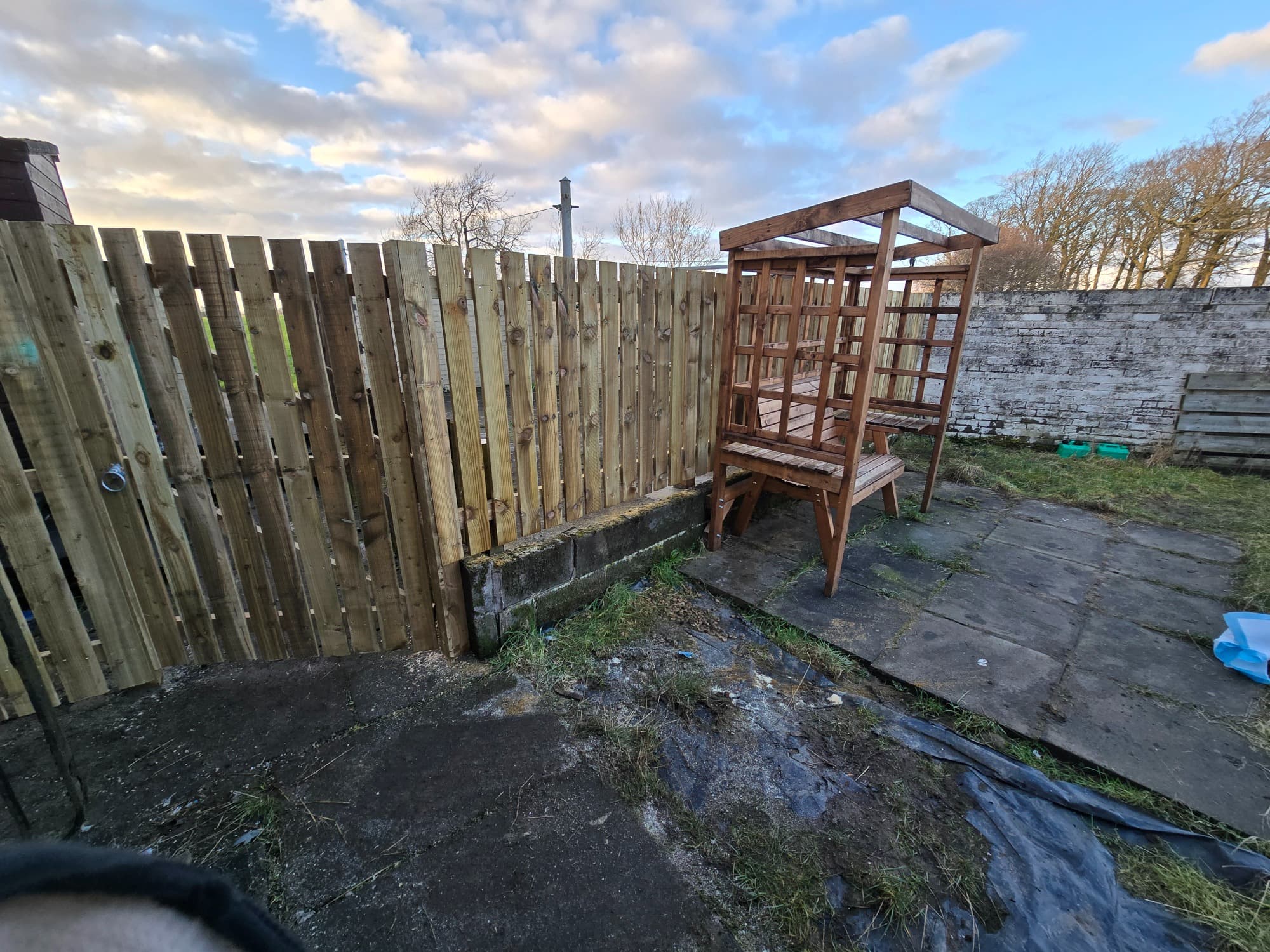 A timber privacy run finished against existing walls, with a matching garden structure alongside.