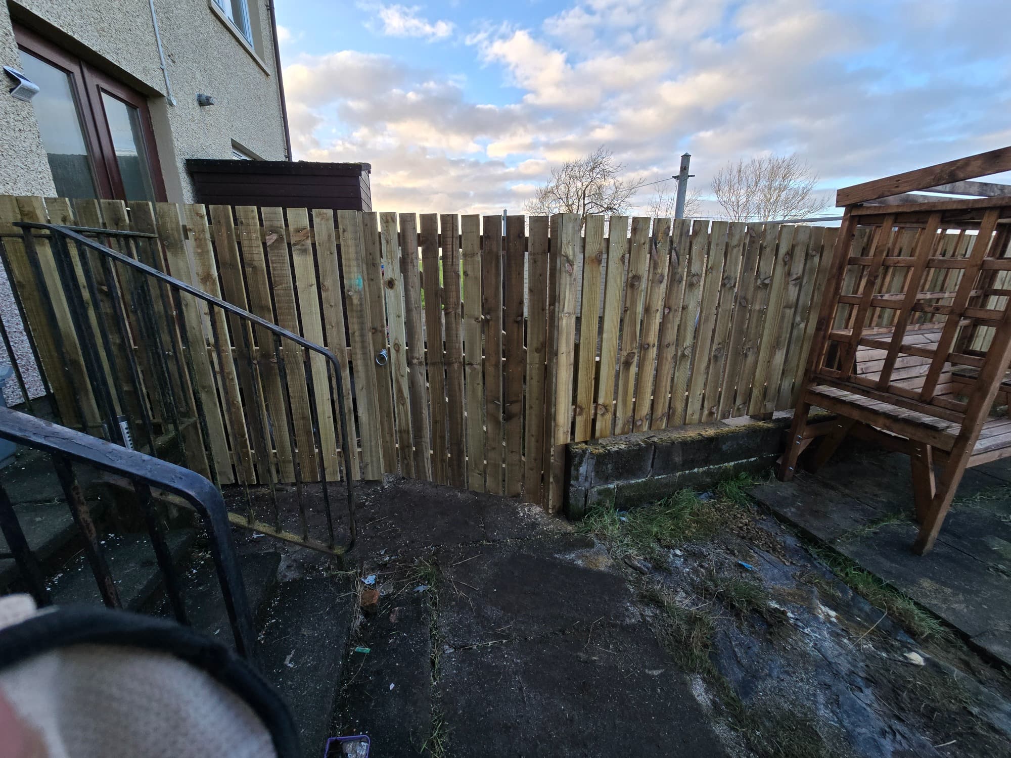 Pressure-treated close-board with a matching gate and ring latch, stepped with the ground.
