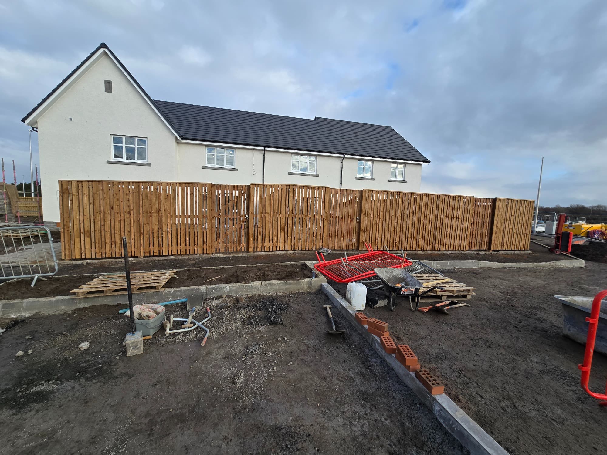 A long close-board boundary with integrated gates on a house just out of the ground.