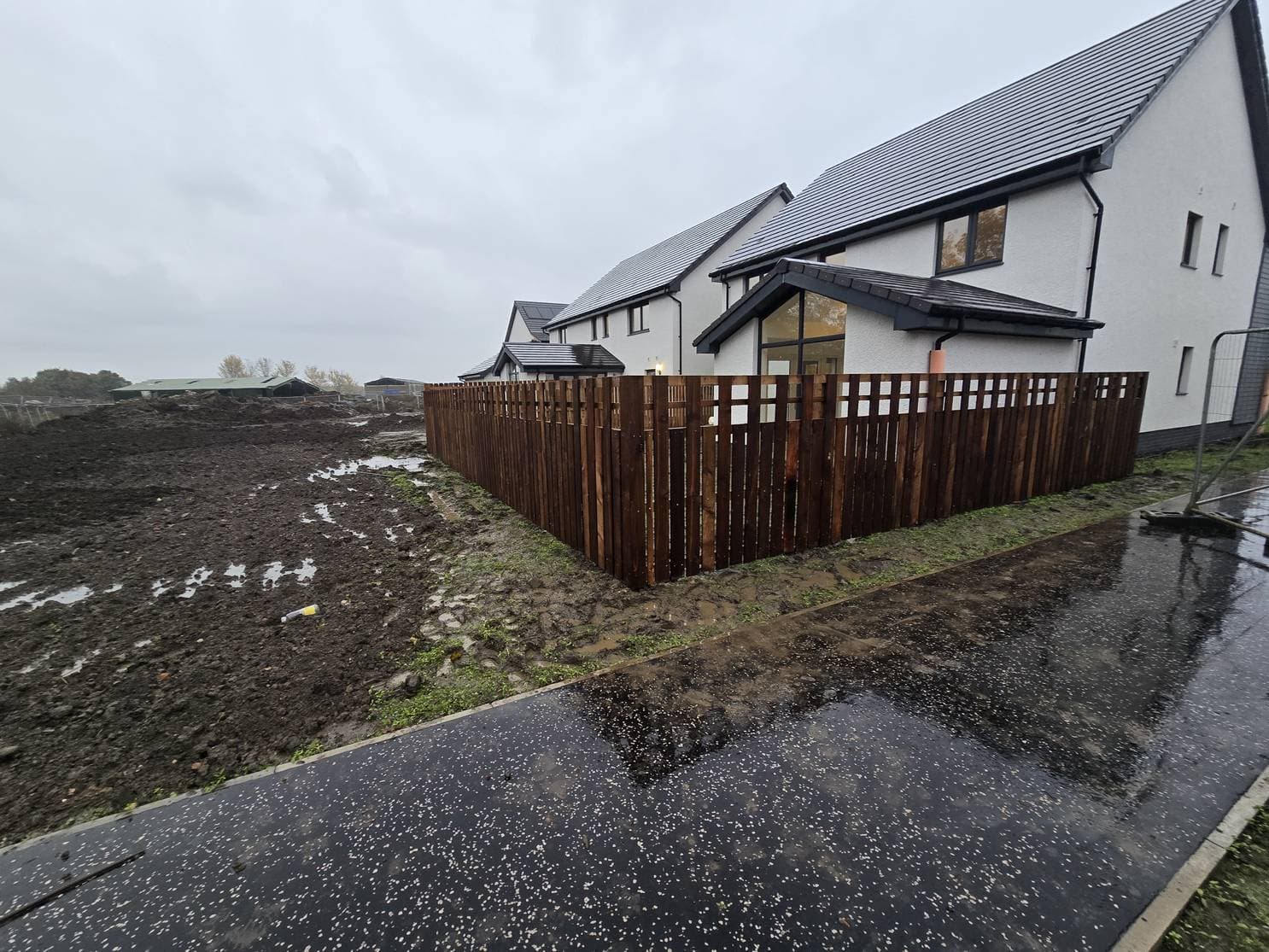 Long vertical-board timber fence along a footpath in East Calder